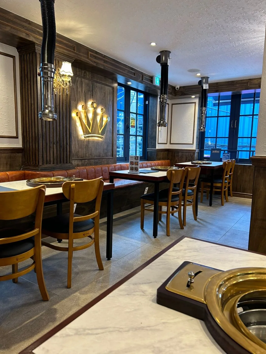 Illuminated crown emblem on walnut wainscoting, with honey-oak chairs